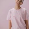 pexels-photo-5701647-5701647 Smiling person in pink shirt symbolizing breast cancer awareness with abstract design.