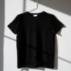 pexels-photo-8532616-8532616-1 Minimalist image of a black t-shirt on a hanger with dramatic shadows on a white wall.
